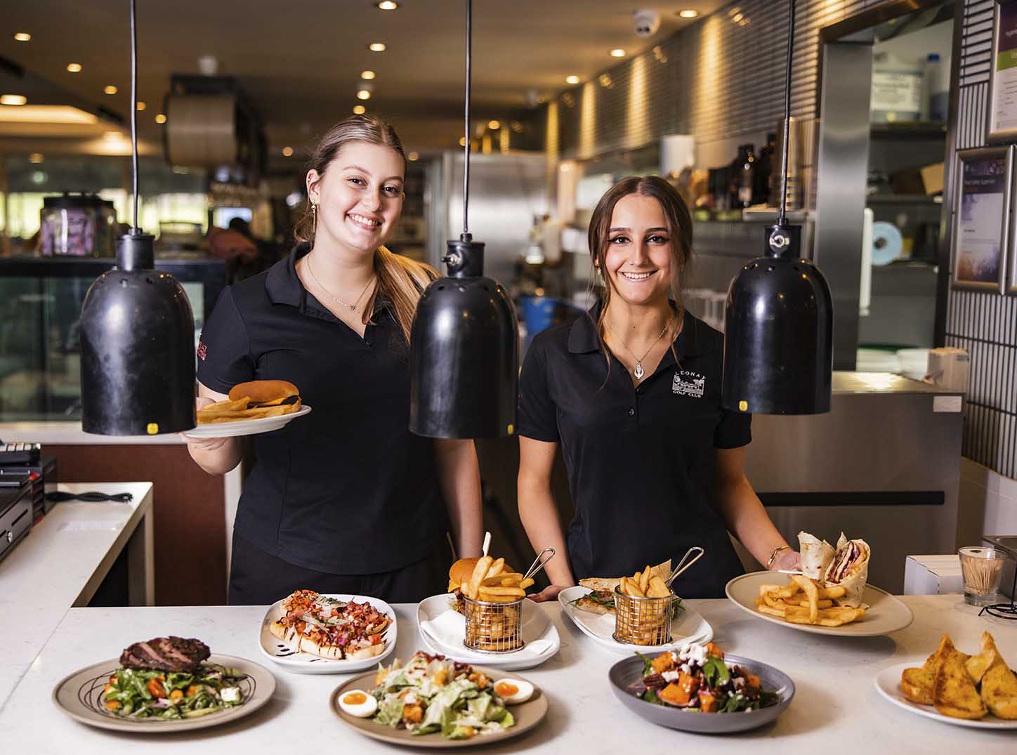 Smiling bar staff holding plates of food at Leonay Golf Club